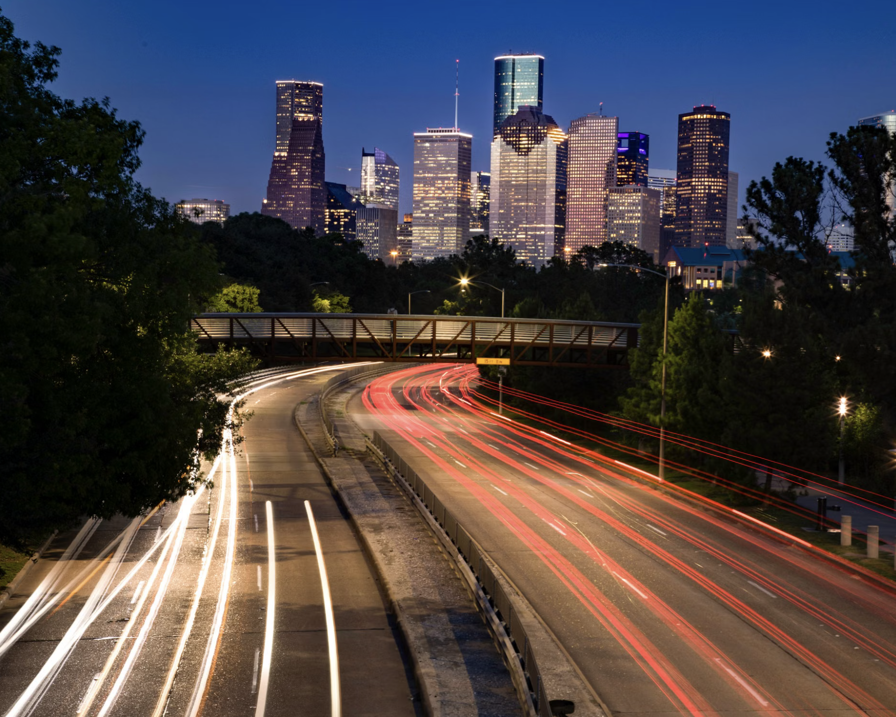 Houston’s illuminated skyline at dusk above sweeping freeway light trails